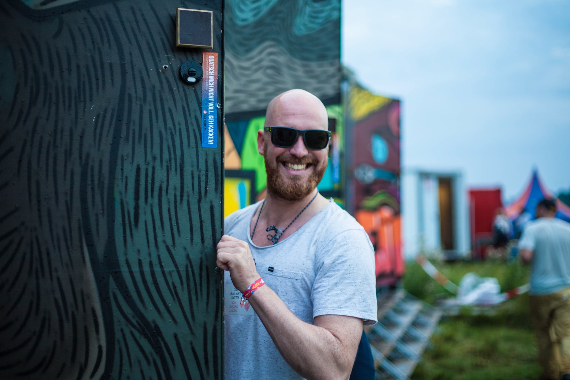 Bild eines Mannes, der lächelnd die Tür eines Komposttoilettenhäuschens öffnet